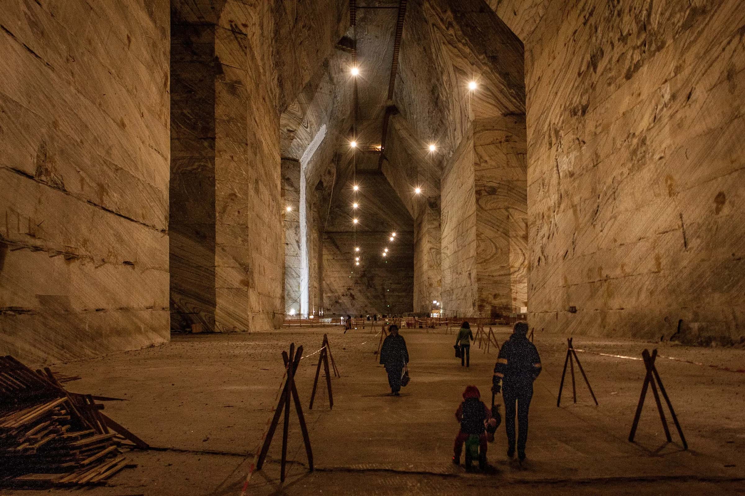 Visitatori che camminano nella vasta sala di sale della miniera di Slănic