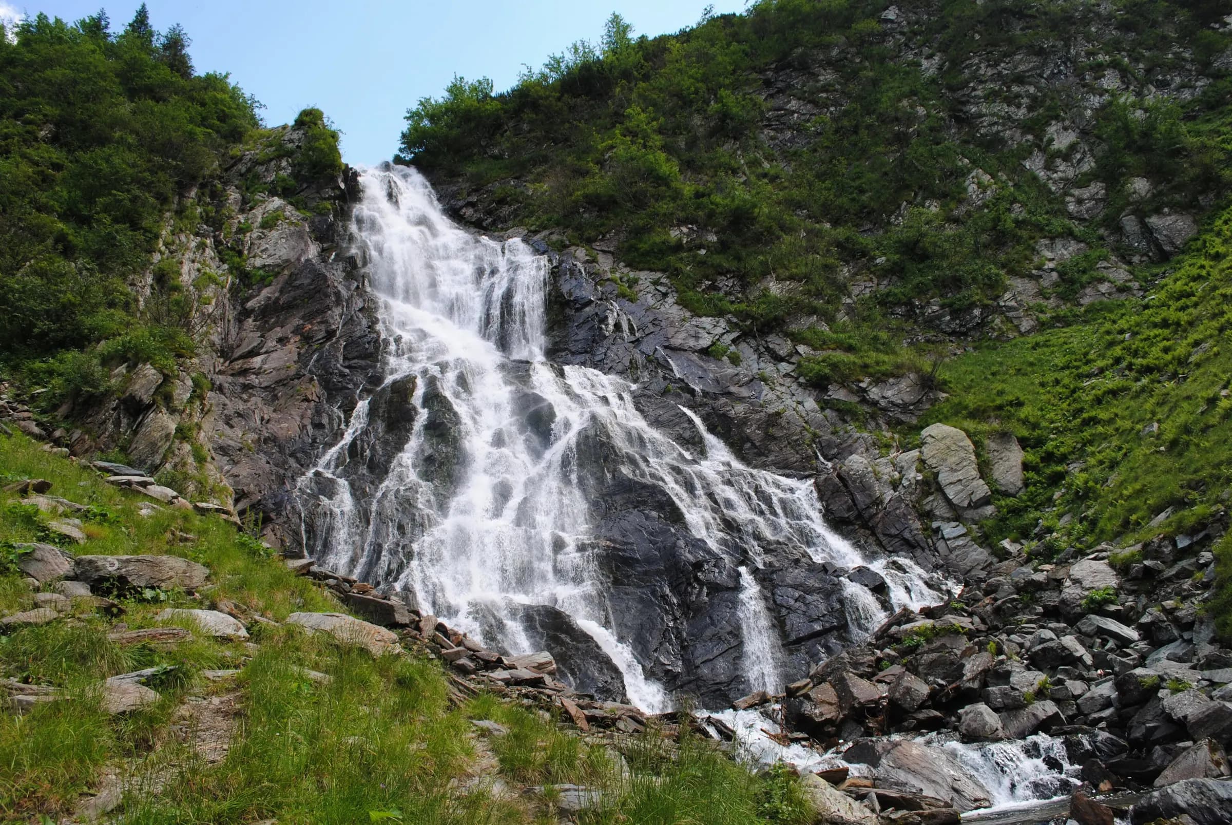Cascada Bâlea curgând pe stânci, într-o vale verde